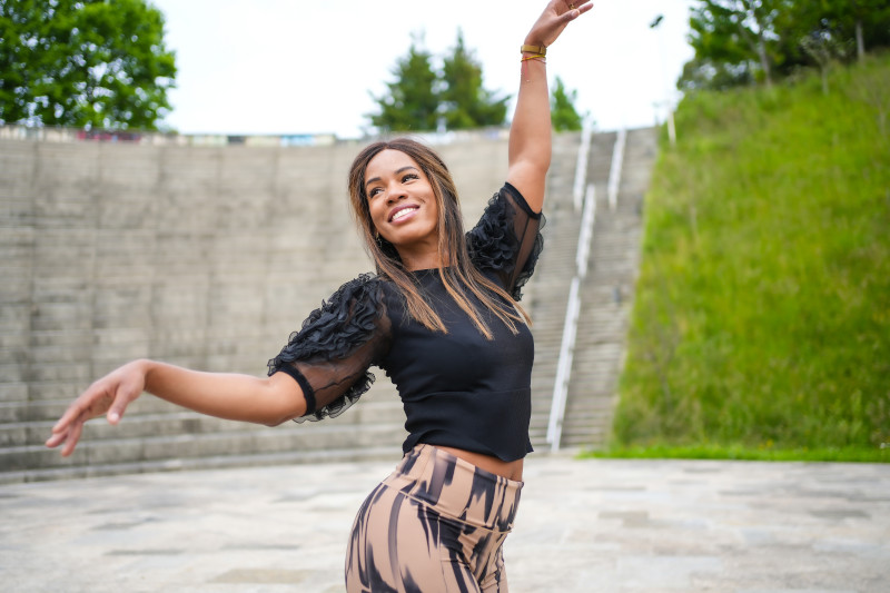 Latin smiling young woman enjoying dancing nia dance alone in a park